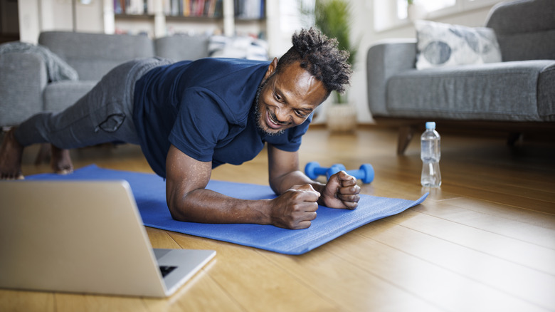Smiling man exercising with instructional video
