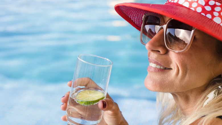 woman at pool drinking sparkling water with lime