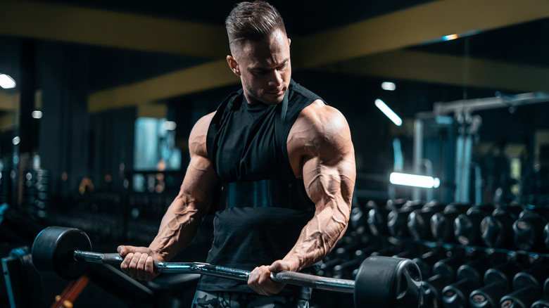 muscular man doing bicep curls at a dark gym