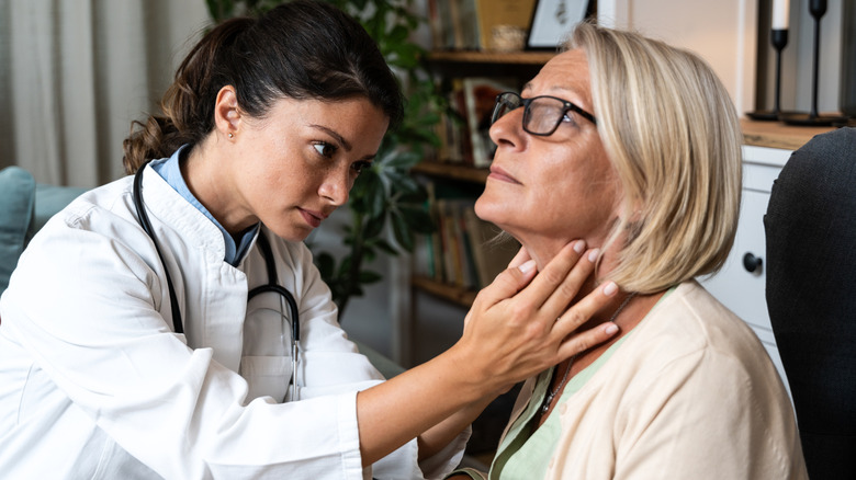 medical staffer checking mature patient thryoid