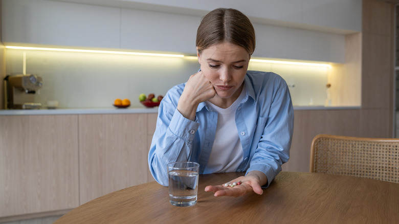 A woman at home staring at the various medications in her hand