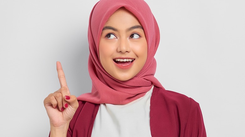Woman in pink hijab pointing up