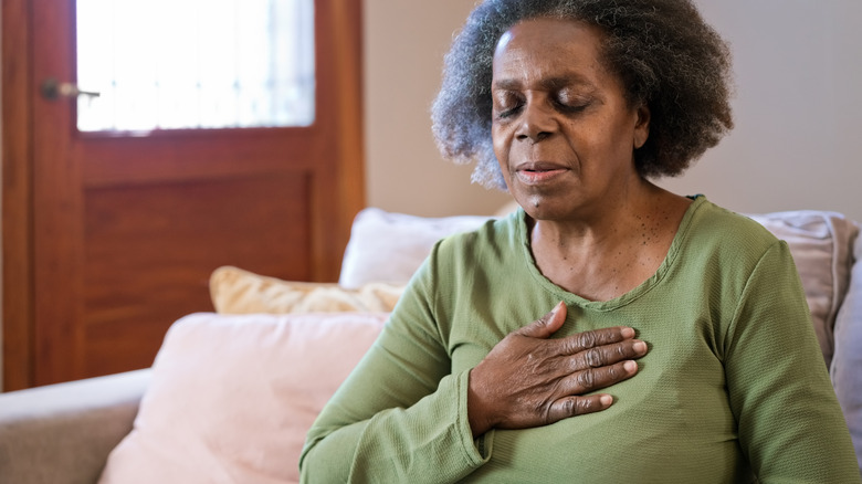 older woman holding her chest