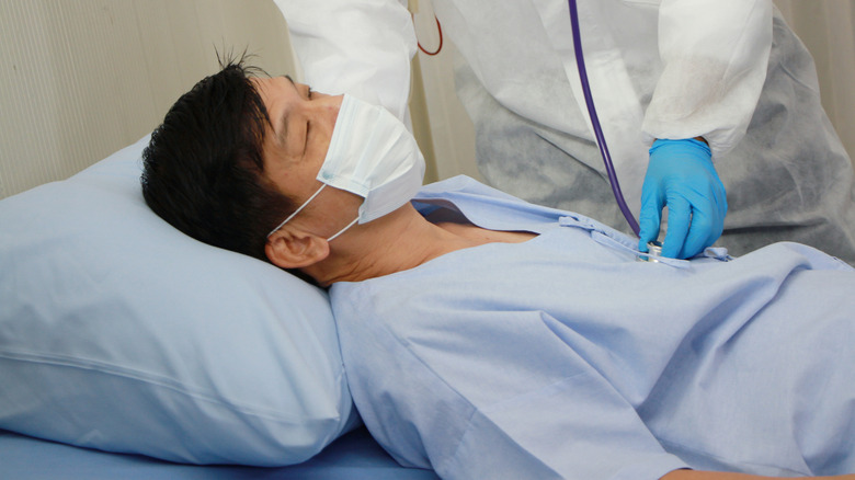 A patient with a virus being treated by a doctor wearing protective equipment