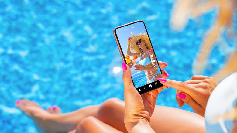 Woman looking a picture of herself by the pool