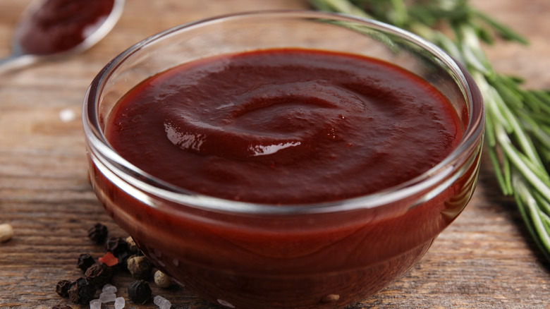 Small glass bowl of BBQ sauce on a wooden table
