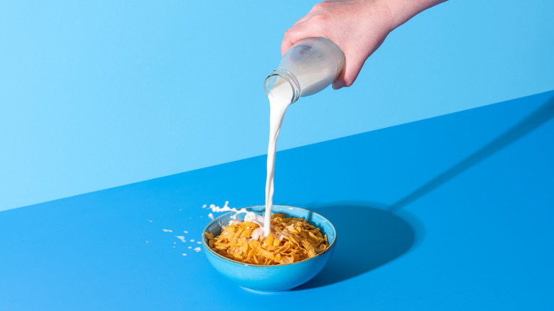 Pouring milk from a bottle into a bowl with cereal