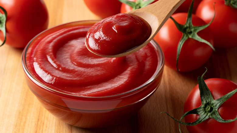 Ketchup in a glass dish and held in a wooden spoon