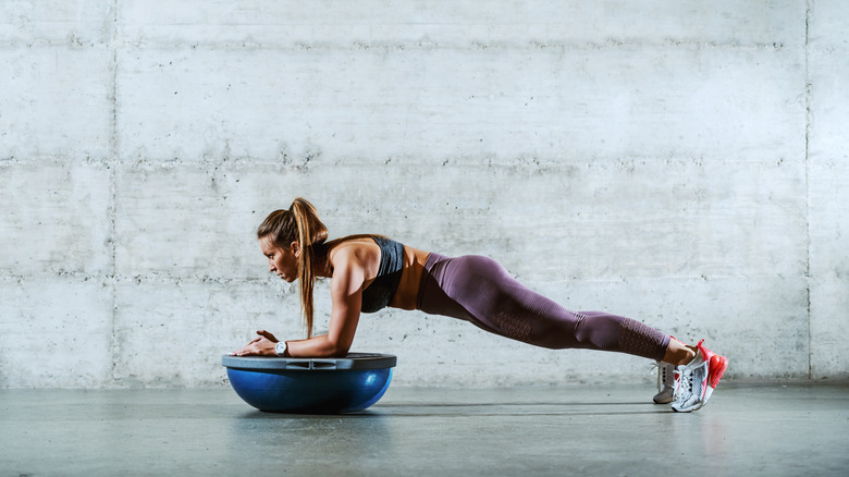 A woman doing planks with a BOSU ball