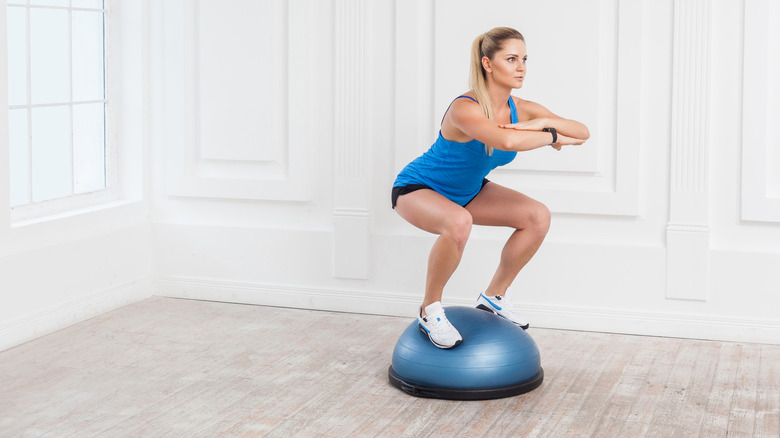 A woman doing a squat on a BOSU ball