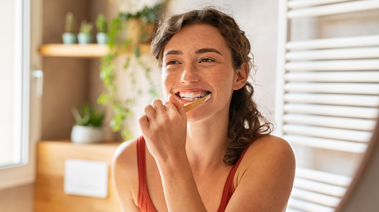 Woman smiling and holding toothbrush in her mouth