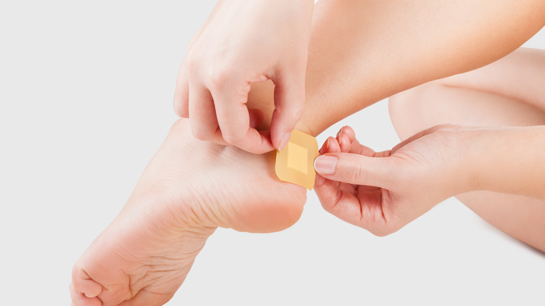 Woman putting bandage on blister