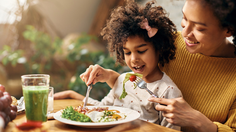 adult feeding child salad