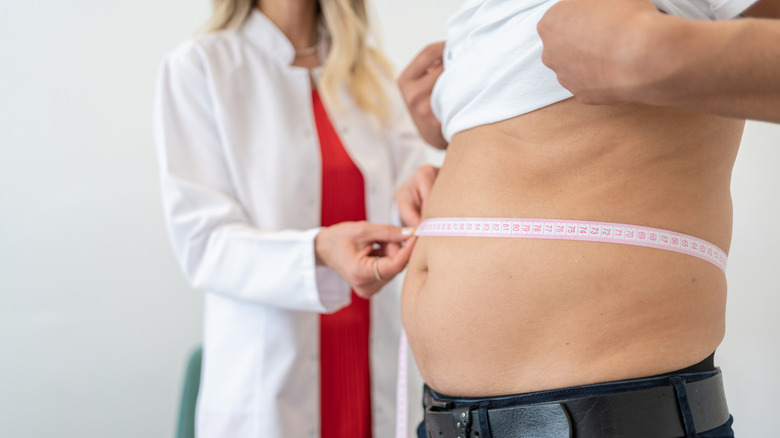 A health professional measuring a man's waist circumference