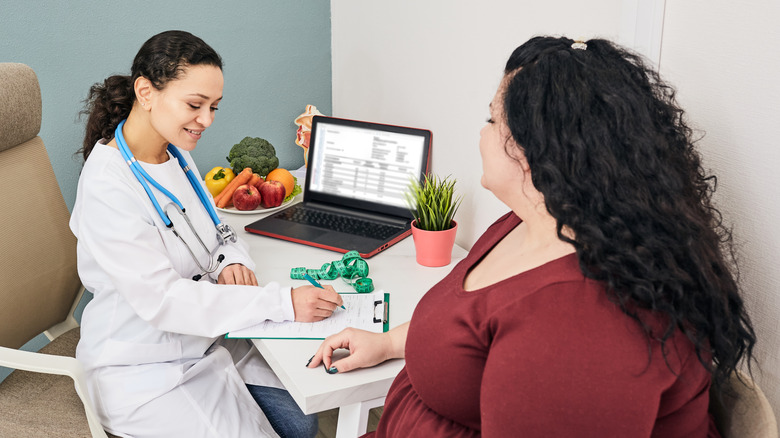 A health professional taking notes while talking to a patient