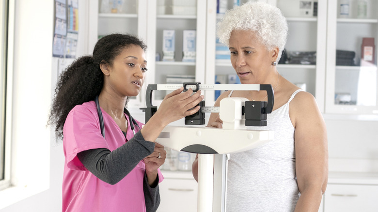 A woman being weighed by a medical professional at a doctor's office