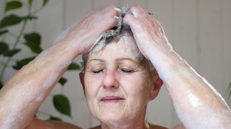 senior woman washing hair in a bathtub