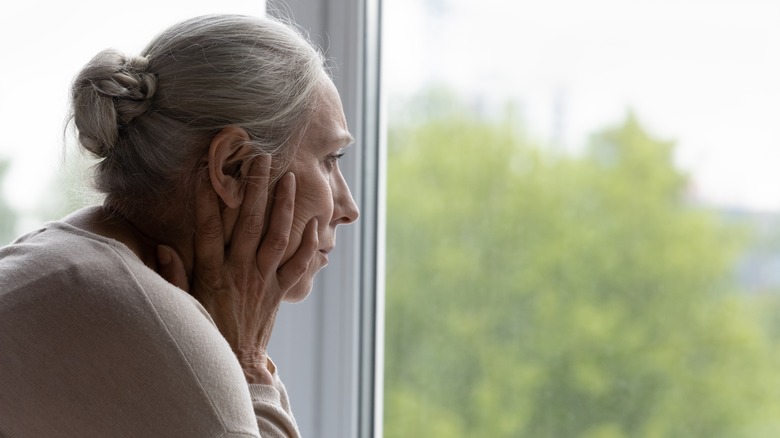 Older woman frowning out window
