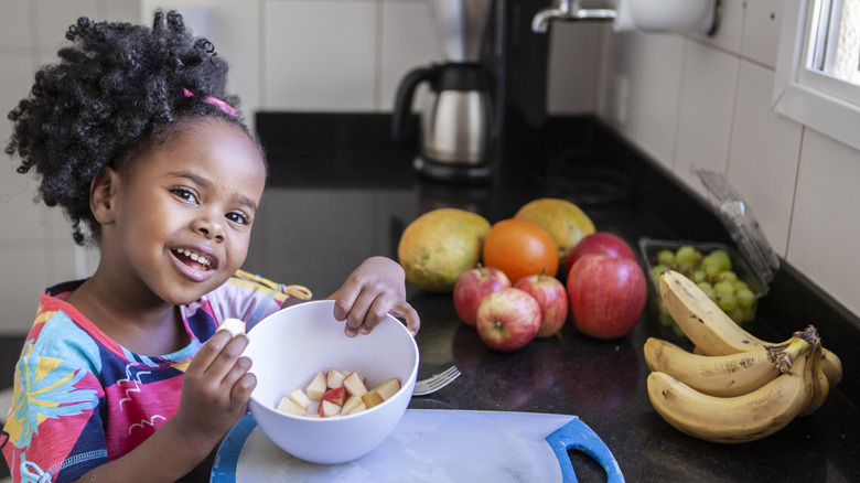 little girl eating fruit in the kitchen