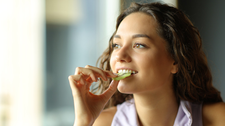 woman eating a slice of kiwi fruit
