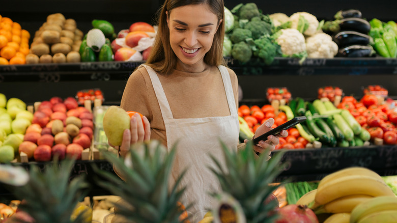 woman reaching for fruit in a grocery