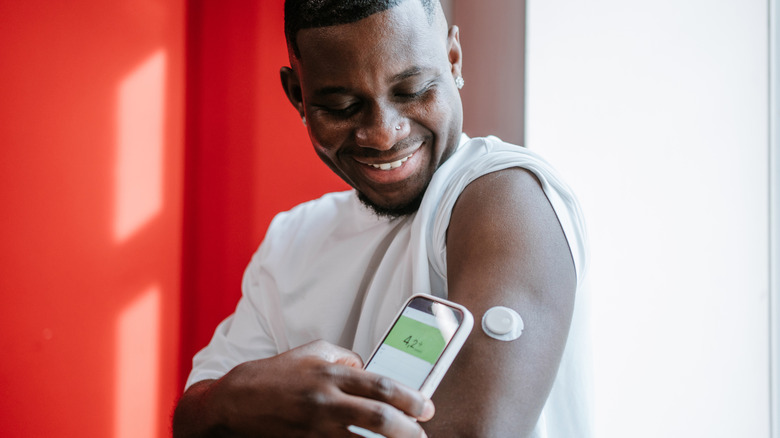man checking blood sugar level with phone