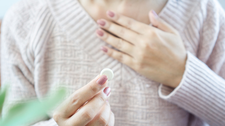 Woman with heartburn holding medication