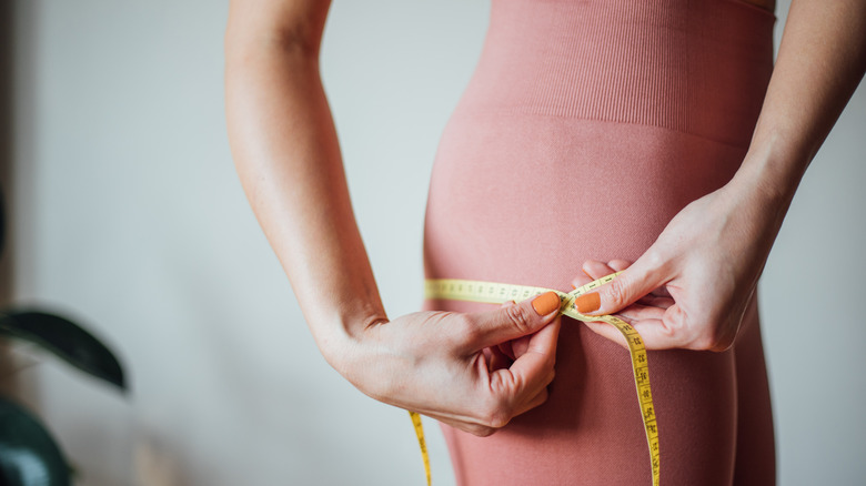 woman measuring butt with tape measure