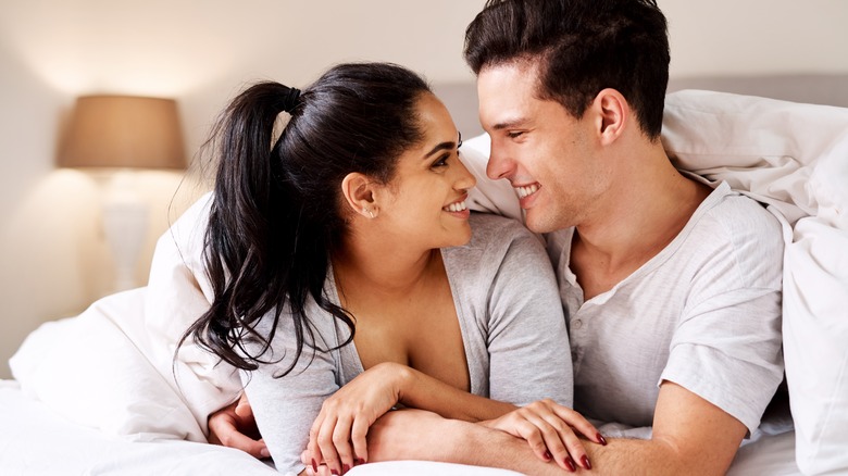 Smiling couple laying in bed
