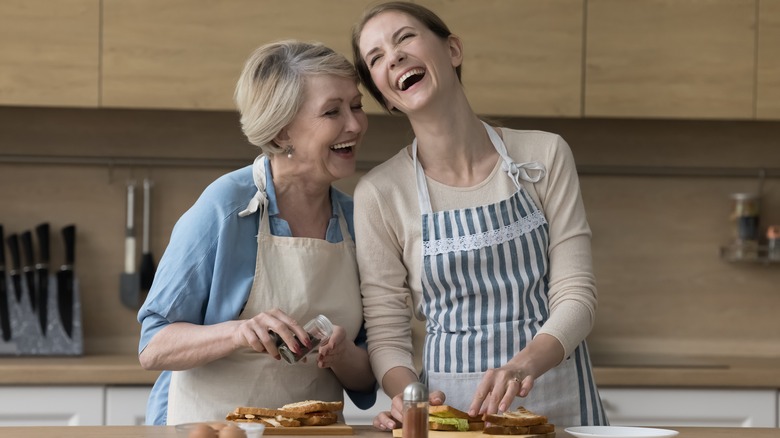 happy older woman and daughter make sandwiches in the kitchen