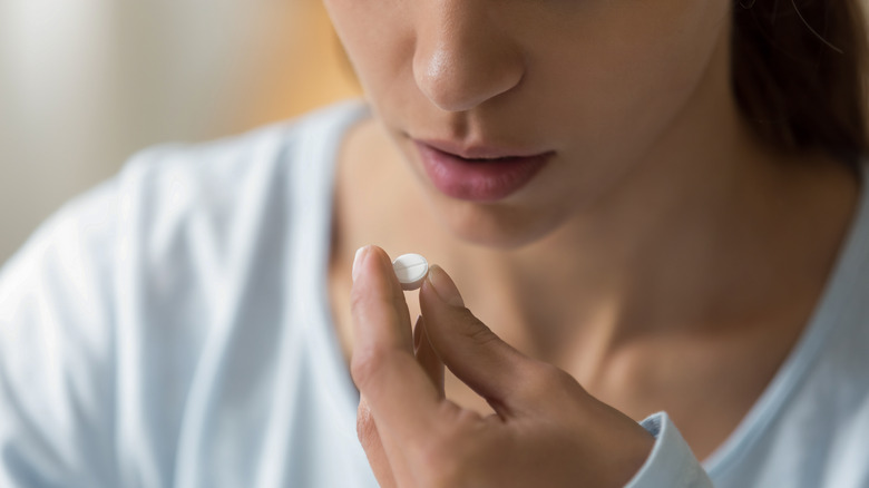 Woman holding white pill