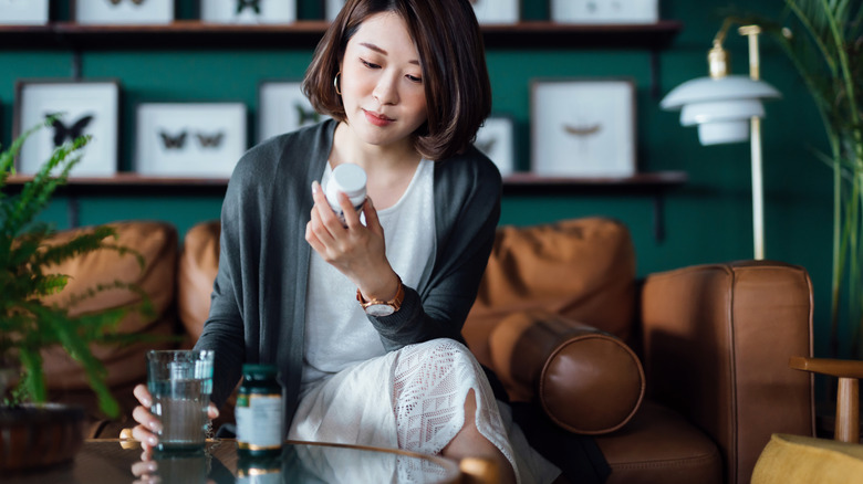 woman reading label of supplement bottle