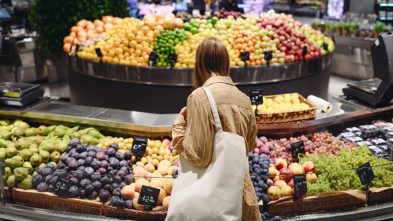 woman from behind looking at assorted fruits in store