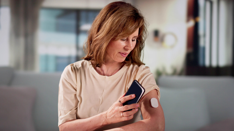 woman checking blood sugar with cell phone app