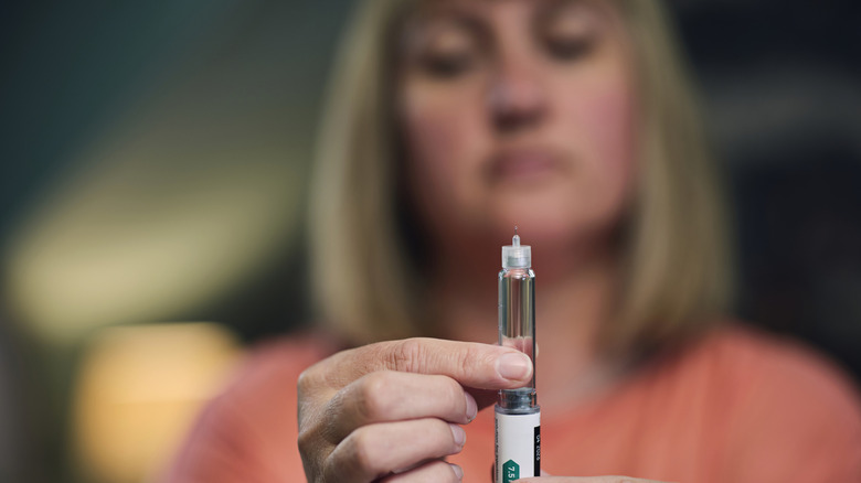 A woman holding a GLP-1 injector pen