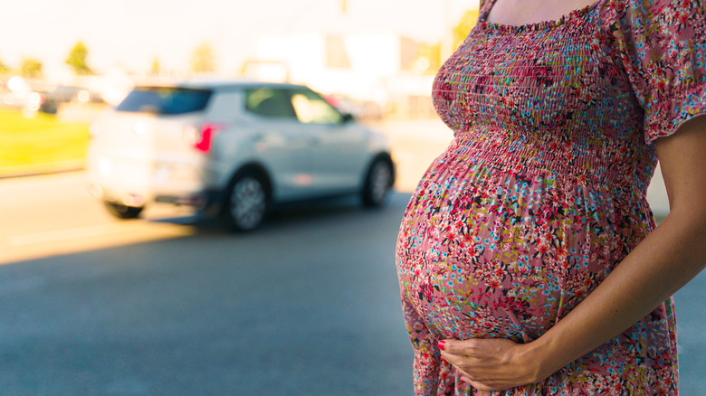 Pregnant woman standing by car