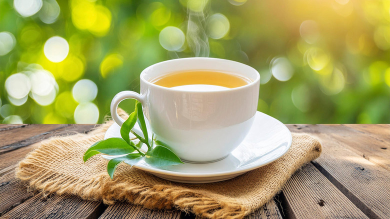 cup of steaming hot green tea on wooden table
