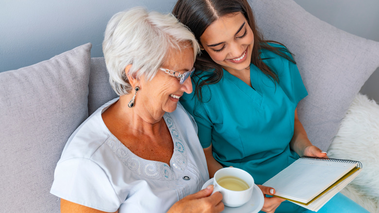 older woman sitting beside nurse drinking green tea