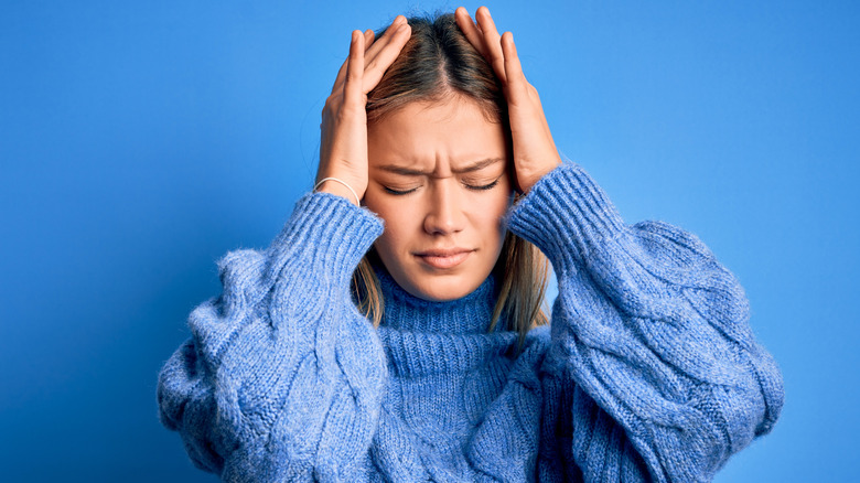woman with hands on head looking stressed