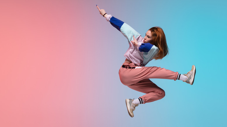 young woman striking a dance pose mid-air 