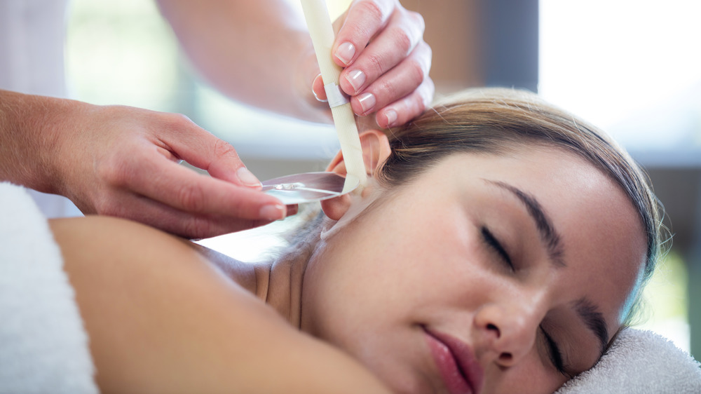Woman receiving ear candle treatment at spa