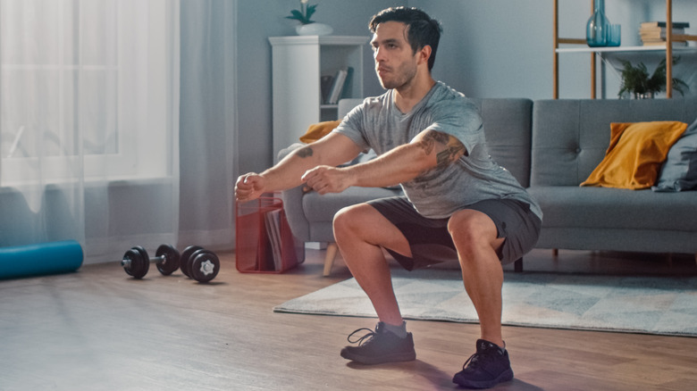 Man performing a squat in his home