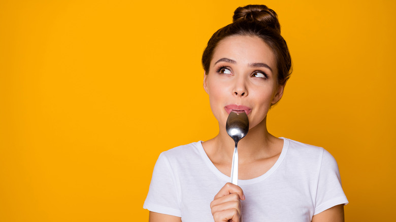 White woman biting spoon