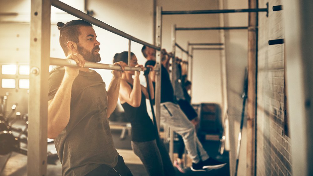 Several people perform pull-ups in a gym