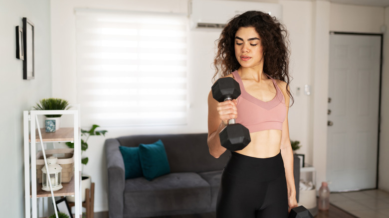 A woman performs bicep curls at home