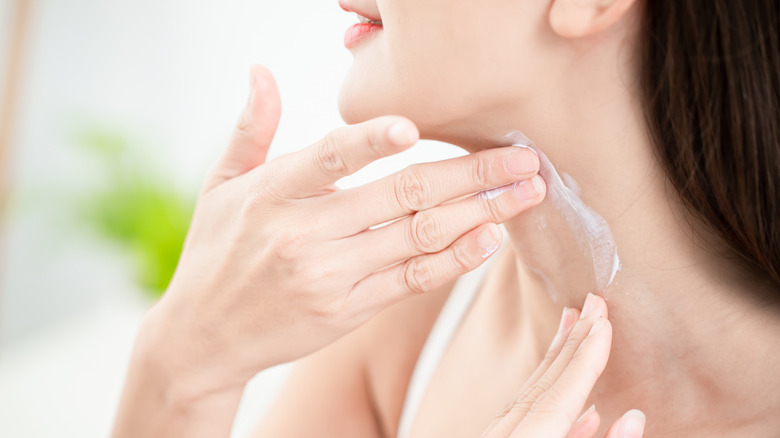 Woman applying sunscreen to neck