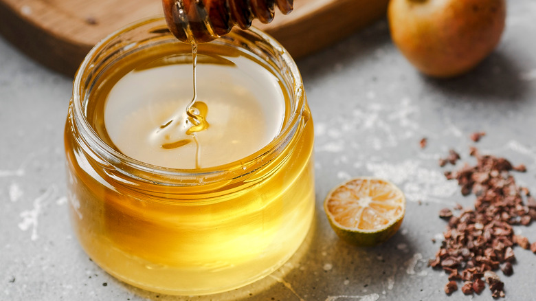 Honey in a decorative jar surrounded by spices