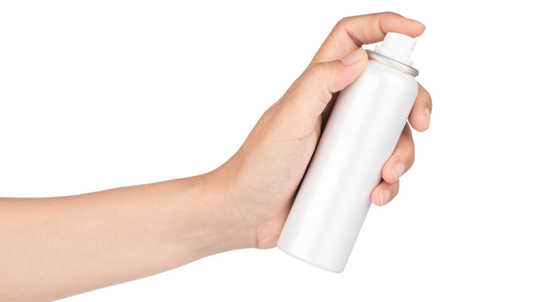 Person holding spray sunscreen bottle