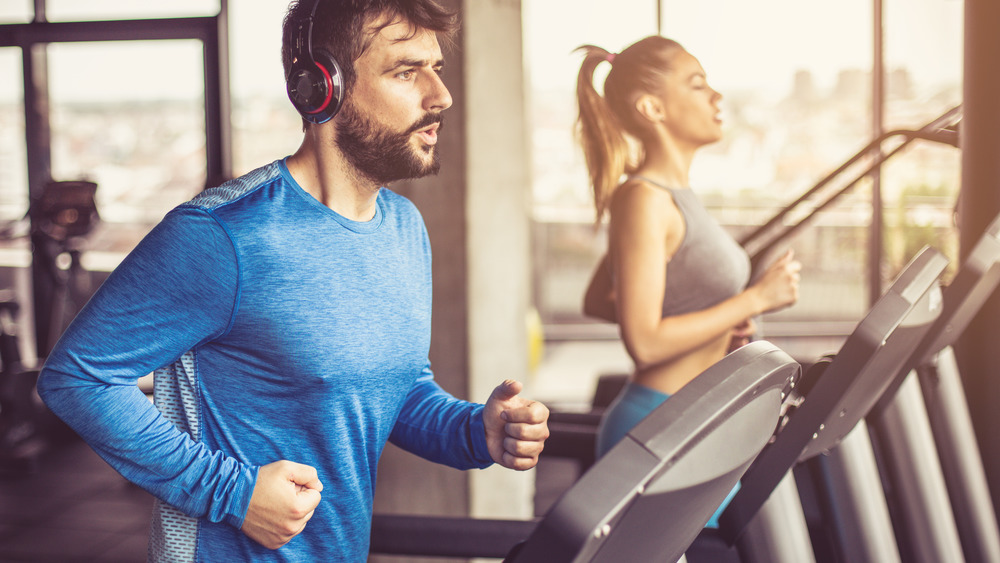 A man and a woman run on treadmills