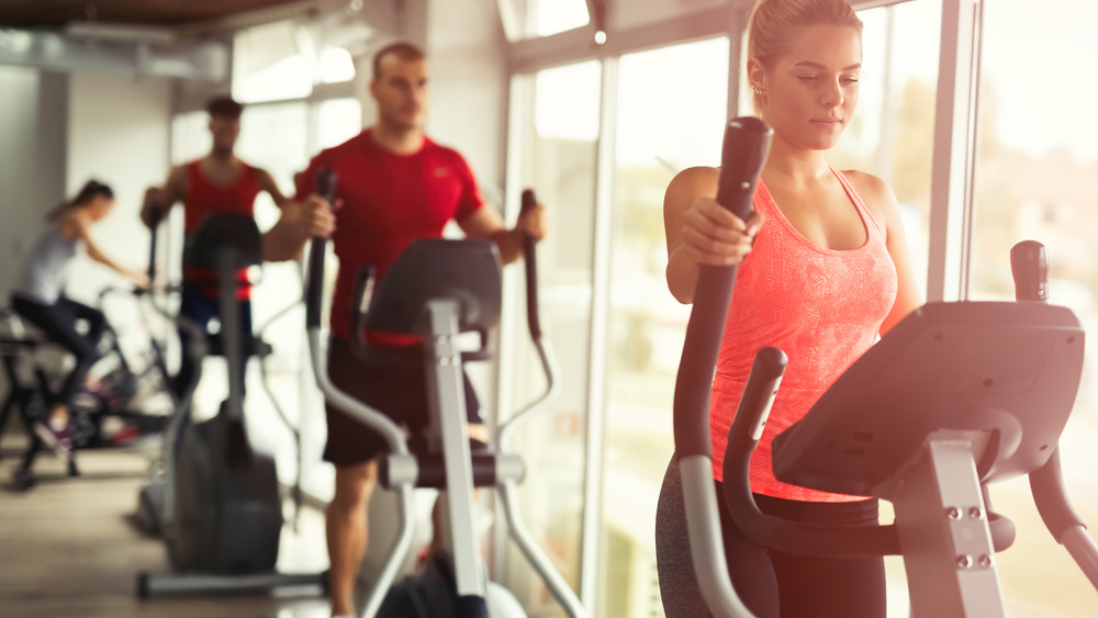 People work on elliptical machines in a gym